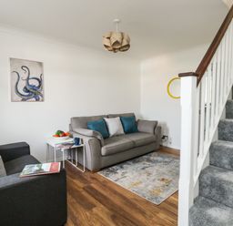 A living room with two sofas a small table with fruit a rug and carpeted stairs at Little Tern Brewers Quay Harbour