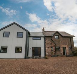 A house with a modern extension and stone facade with gravel driveway at Shepherds House in Lowick