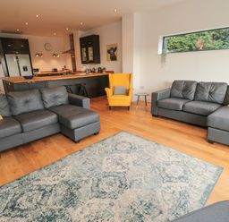 A living room with two gray sofas and a yellow armchair next to an open kitchen at Shepherds House in Lowick