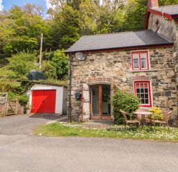 An outdoor area with a stone cottage and garden furniture at Sycamore Vestry in Pontfaen near Fishguard
