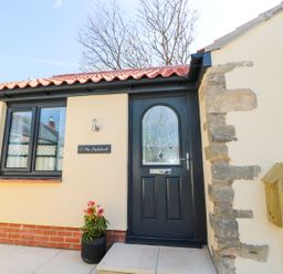 A front door with decorative glass window and a potted plant outside at 3 The Paddock in Benthall near Beadnell