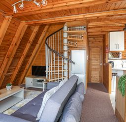 A living area with a gray couch coffee table with fruit spiral staircase and kitchenette at 171 Snowdonia View in Chwilog