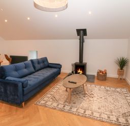 A living room with a blue sofa a coffee table a fireplace a rug and a television at Beudy in Llangefni