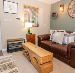 A living room with a brown leather sofa and wooden coffee table at Cwm Caeth Cottage in Nantmor near Beddgelert