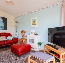 A living room with a red couch and television at Chi Prenn Byhan in Tintagel