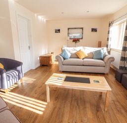 A living room with sofas a coffee table and curtains at Awel Y Berwyn in Llangynog