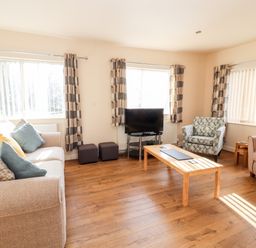 A living room with two sofas an armchair wooden coffee table and a television at Awel Y Berwyn in Llangynog