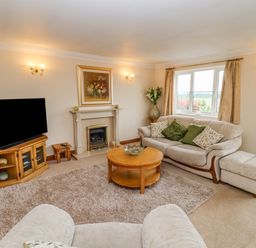 A living room with a sofa a television a fireplace and a round wooden coffee table at Corner House in Cinderford
