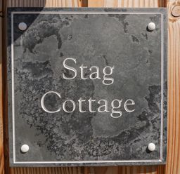 A slate sign with the text Stag Cottage mounted on wooden surface at Stag Cottage in Lytchett Matravers
