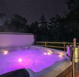 A hot tub with purple lights and a champagne bucket at Stag Cottage in Lytchett Matravers