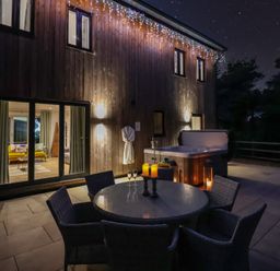An outdoor area with a dining table and hot tub at Stag Cottage in Lytchett Matravers