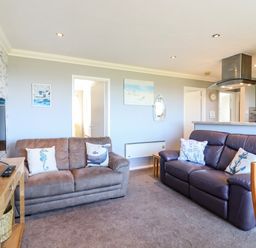 A living room with two sofas a wooden TV stand and wall art at Bungalow 14 in Corton