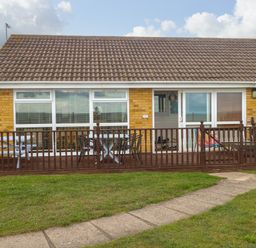 A bungalow with a tiled roof a wooden deck and outdoor furniture at Bungalow 14 in Corton