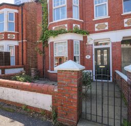 A brick townhouse with a black front door behind a metal gate at Apple Tree House in Hunstanton