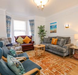 A living room with sofas armchairs a coffee table and colorful cushions at Apple Tree House in Hunstanton