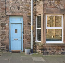 A blue door and a window on a stone building with a potted plant and a street lamp at The Lazy Seal in Spittal