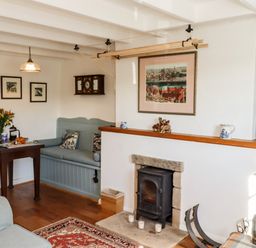 A living room with a wood stove fireplace a built in bench and a small dining table at Michaelmass Cottage in Castleton