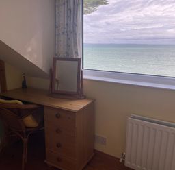 A wooden desk with a mirror and chair beside a window showing a sea view at Rocklea Seaside Cottage in Newcastle County Down