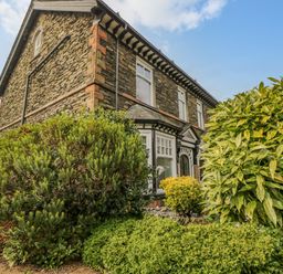 Exterior view of a stone house with large bushes in front at Hollywood in Windermere