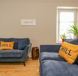 A living room with two blue sofas and yellow pillows with chill text with plants near a window at Hollywood in Windermere