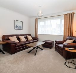 A living room with brown leather sofas a coffee table and lamps at 3 Granbrook Lane in Mickleton Gloucestershire