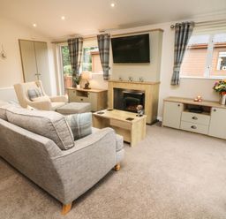A living room with a sofa armchair coffee table fireplace and television at The Warren in Hellifield