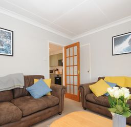 A sitting room with two brown sofas with cushions and a vase of white flowers on a wooden table at Sea Spray in Port Isaac