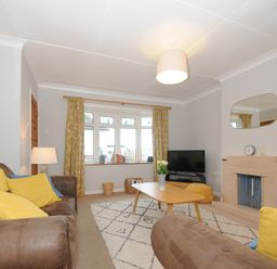 A living room with brown sofas yellow and blue cushions a wooden coffee table a fireplace and a television at Sea Spray in Port Isaac