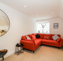 A living room with a red corner sofa and round mirror on the wall at Bayview Loft in Weymouth