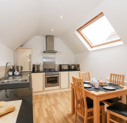 A kitchen with wooden flooring dining table and chairs stove sink and skylight window at Bayview Loft in Weymouth
