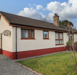 A bungalow with a satellite dish and a grassy front yard at The Hideout in Portree