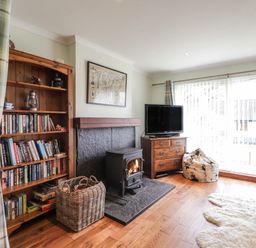 A living room with a bookshelf a wood stove a television on a wooden cabinet and a bean bag chair at The Hideout in Portree