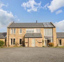 A stone farmhouse with multiple windows and a gravel driveway at Fontburn Farmhouse Ewesley near Rothbury