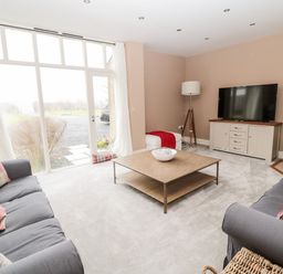 A living room with two sofas and a coffee table in front of a large window at Fontburn Farmhouse in Ewesley near Rothbury
