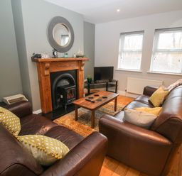 A living room with two brown leather sofas a wooden coffee table a fireplace and a TV at Pebble Lodge in Kenmare County Kerry