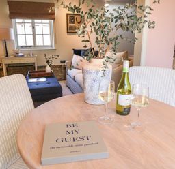 A dining table with a guestbook a bottle of wine and two wine glasses in a living area at The Forge in Old Newton near Stowmarket