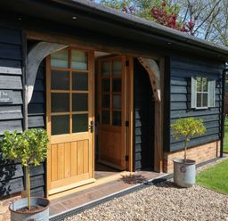 An entrance to a building with wooden doors and potted plants outside at The Forge in Old Newton near Stowmarket