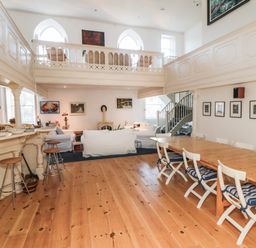 A living and dining area with a wooden table and chairs near a bar with stools and white sofas at Bethel Chapel Staithes