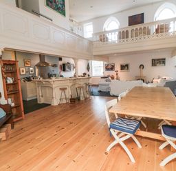 An open plan living area with wooden dining table and chairs a kitchen bar with stools and a sitting area with sofas at Bethel Chapel in Staithes