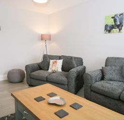 A living room with two grey sofas a wooden coffee table a floor lamp and animal pictures on the wall at Oxen Park Farm Cottage Oxen Park near Ulverston