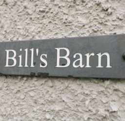 A close up of a wall sign reading Bills Barn on a textured exterior wall at Bills Barn Oxen Park near Ulverston
