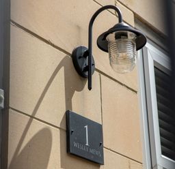 A wall-mounted light and house number sign on a building exterior at 1 Wesley Mews in Alnwick
