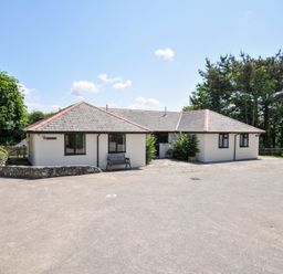 A house with a bench and trees in front at Columbine Cottage in Bude