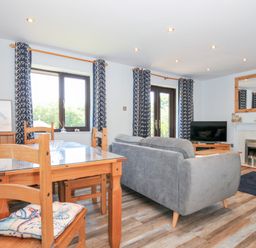 A living room with a dining table and sofa at Columbine Cottage in Bude