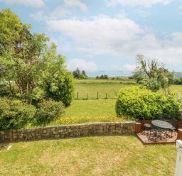 A garden with a table and chairs at Bryn Awel in Mynytho near Abersoch