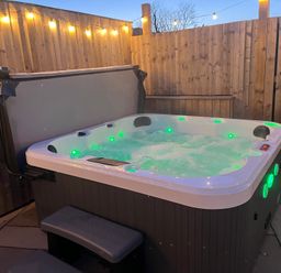 A hot tub with steps and wooden fence in an outdoor space at Gilfach in Abersoch