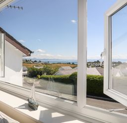 A view through open windows overlooking houses trees fields and the sea at The Anchorage in Abersoch