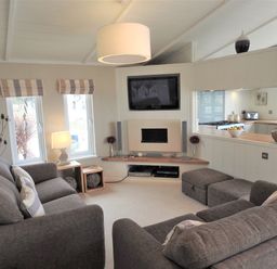A living room with two gray sofas a wall-mounted TV and a fireplace at The Warren D26 in Abersoch
