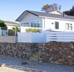 A house with a stone wall and fence at The Warren D7 in Abersoch