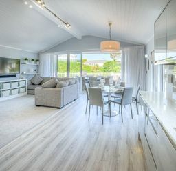 An open plan living room dining area and kitchen with a grey sofa dining table and chairs at The Warren Q4 in Abersoch